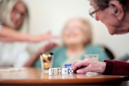 Residents at a care home enjoy an activities session including dominoes