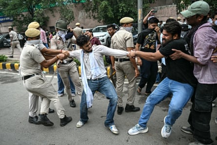 A police officers pulls a man by the arm as another protesters pulls his other arm