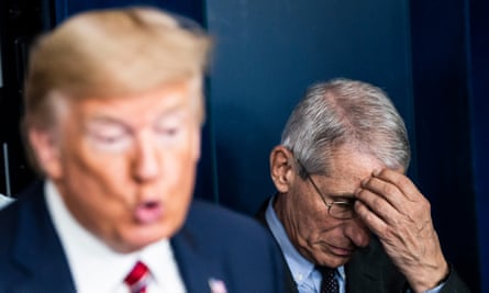 Fauci listens to Trump at a briefing on 20 March.