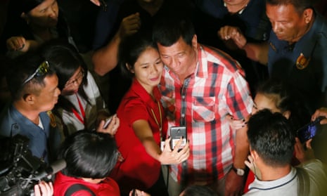  Rodrigo Duterte poses for a selfie with a supporter in his hometown in Davao city.