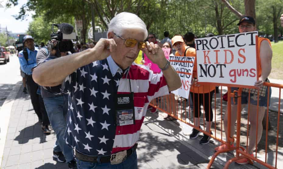 A member of the National Rifle Association plugs his ears with his fingers as he walks past protesters during the NRA's annual meeting in Houston on Friday.