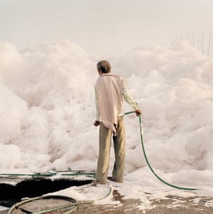 Um trabalhador com uma mangueira de água tenta domar um iceberg de espuma criado pelos resíduos químicos despejados pelas fábricas ao longo do rio Yamuna, Delhi, 2015