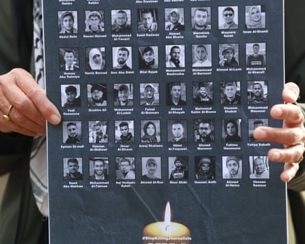 A person holds up a placard bearing images and names of people killed
