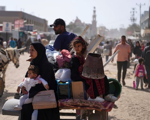 Una familia con sus pertenencias en la parte trasera de un carro en una carretera de Gaza.