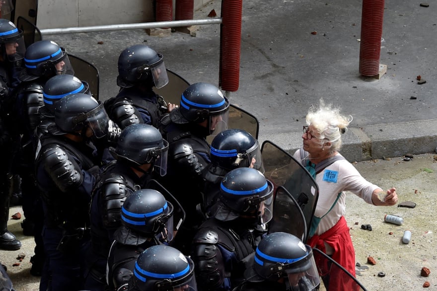 A woman stands in front of police officers as they block access to a street during a protest against proposed labour reforms in Paris on 14 June, 2016.