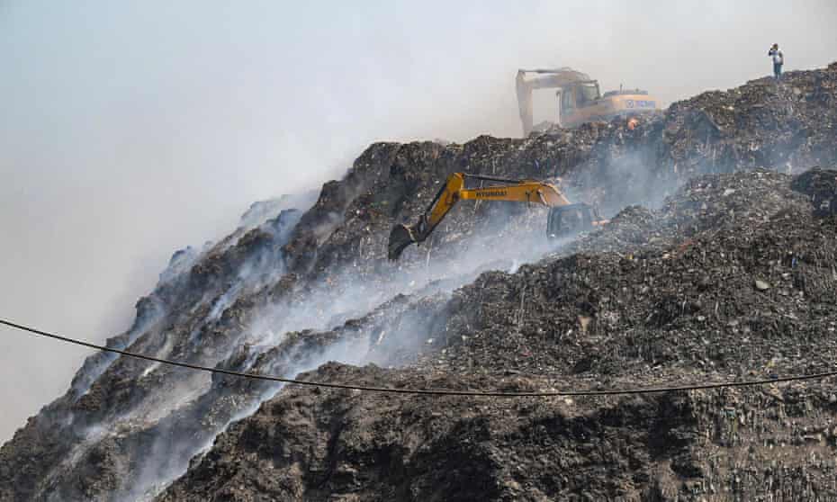Excavators working in a landfill on fire.