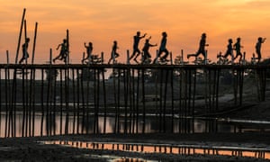 wooden bridge in Majuli with running people