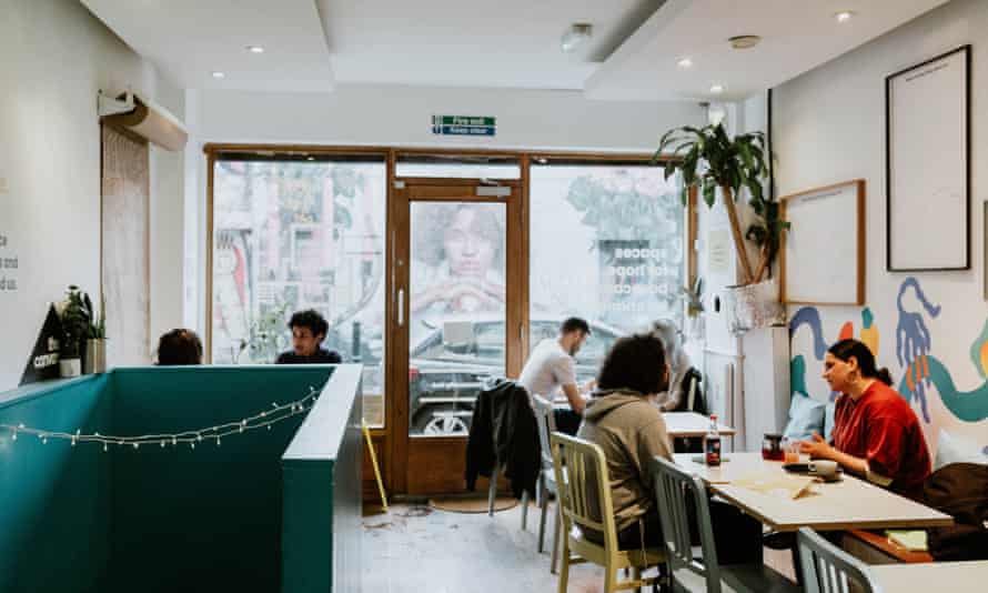 A cafe with multiple people sat drinking and eating.