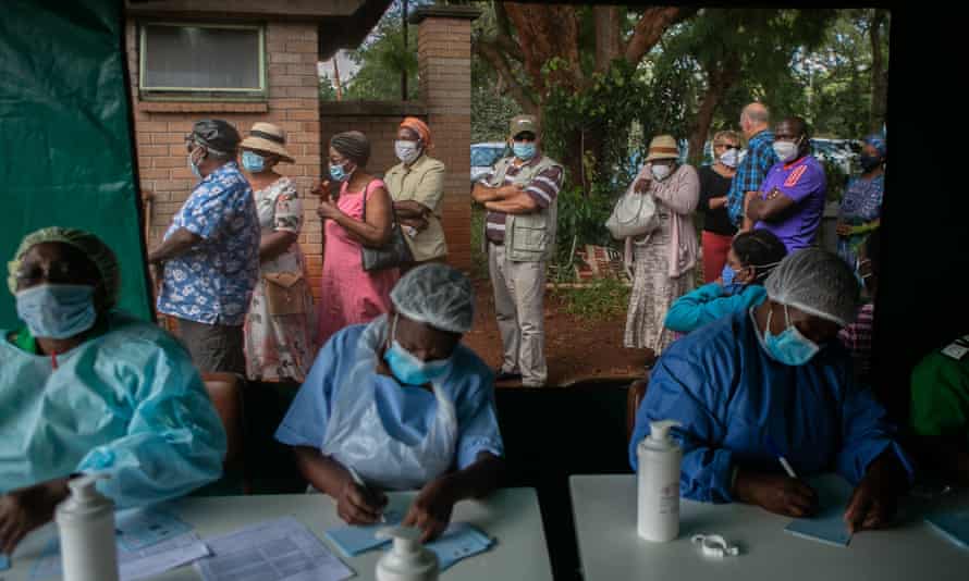 Elderly people queue for the Sinopharm vaccination outside the tent while nurses prepare paperwork at a local hospital on 29 March in Harare, Zimbabwe.
