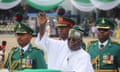 Bola Tinubu raises his hand flanked by military officials during an honour guard