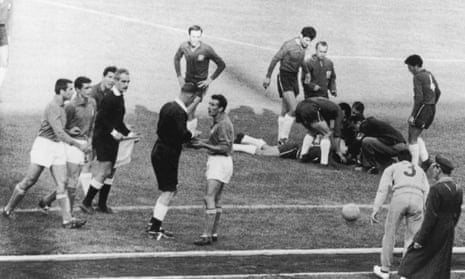 English referee Ken Aston sends off Italian player Mario David, while an injured Chilean player lies on the ground, during the 1962 World Cup meeting.