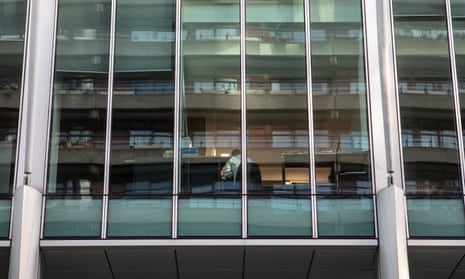 A lone worker seen through the windows of a near-empty office block in the City of London