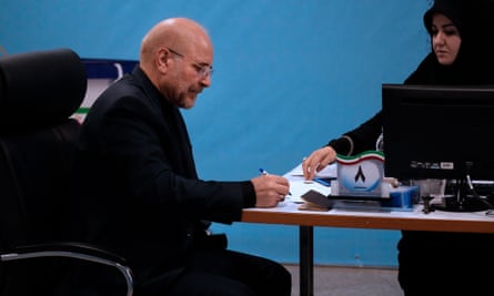 Mohammad Bagher Qalibaf sitting at desk writing with woman all in black at the other side of the desk