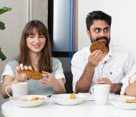 A woman and man seated at a table taste-testing Anzac biscuits.