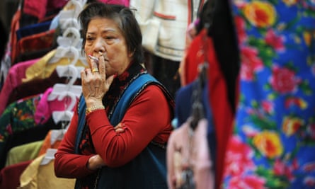 A street market vendor smokes a cigarette as she waits for customers at her clothes stall in Hong Kong.
