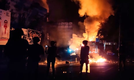 Security forces watch as a building burns after hundreds of demonstrators marched near Papua’s biggest city Jayapura on Thursday night.
