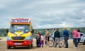 People queue up at a Mr Whippy ice cream van that is parked on a beach