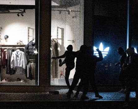 Rioters smash a shattered Adidas store window at night in Paris