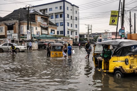 Pedestrians wade through a flooded street in Lagos on 3 July.