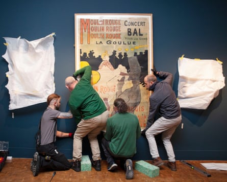 Four people hanging a large print on a blue wall