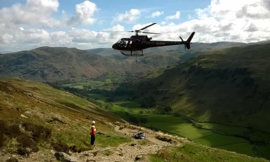 A helicopter delivers material for repair work, Ullswater Valley, Lake District.