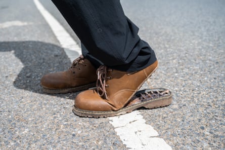 Cropped shot view of someone trying to walk on the road while wearing broken leather shoes.