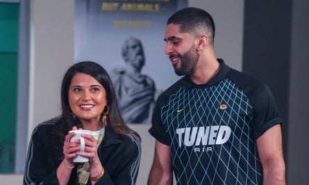 A woman smiles while holding a mug while a taller man looks down to her smiling