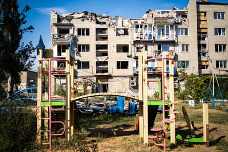 A severely damaged block of flats, with a playground in the foreground