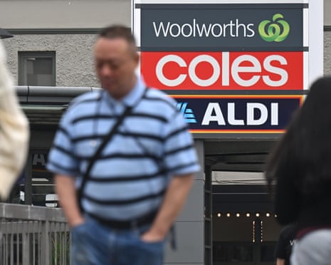 Shoppers walk past signs of Kmart, Woolworths, Coles and Aldi at a shopping centre