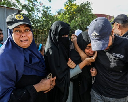 A man and woman try to comfort a weeping woman as another crying woman stands alongside