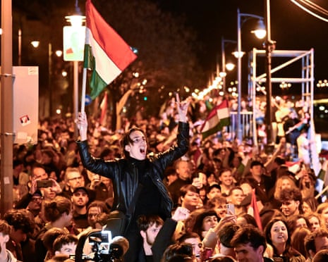 A man waves a Hungarian flag as he celebrates in the streets after the announcement of partial results of the Hungarian parliamentary election in Budapest, Hungary.