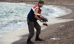 A police officer carries the lifeless body of Alan Kurdi