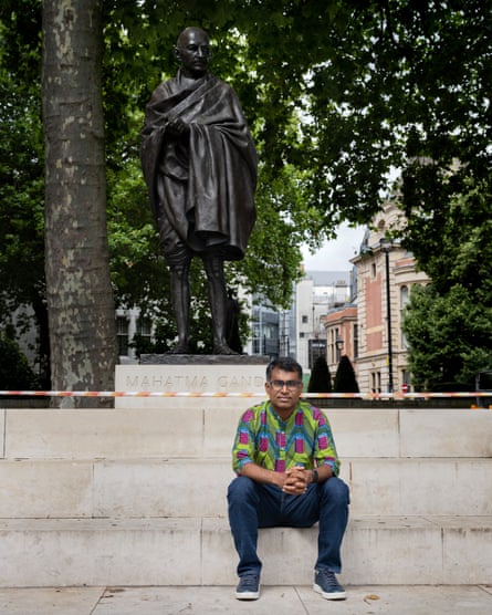 Danny Sriskandarajah, the Sri-Lanka-born British-Australian chief executive of the UK thinktank the New Economics Foundation, sitting on steps at Parliament Square in front of a statue of Mahatma Gandhi