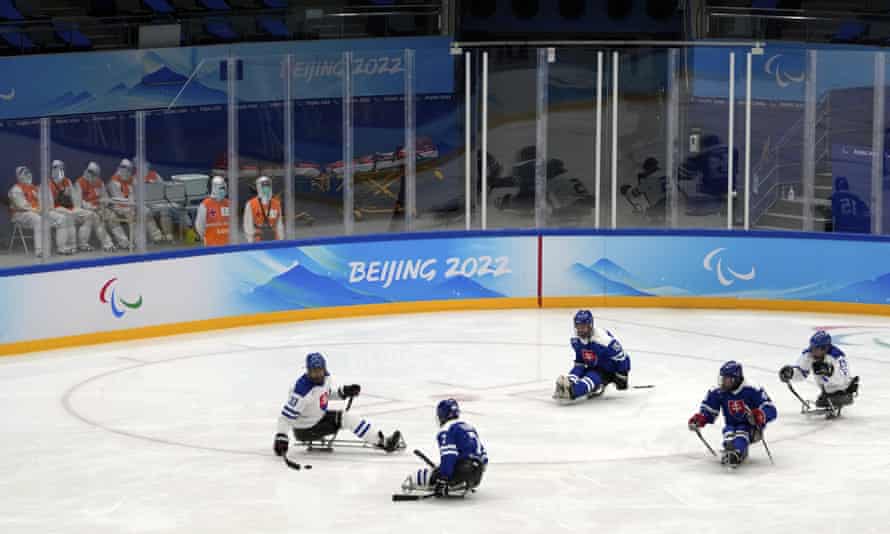 Medical workers wearing protective suits watch Slovakian players during a para ice hockey practice session