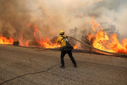 A firefighter aims water at the flames of a backburn as the Fairview Fire grows near Hemet on Wednesday.