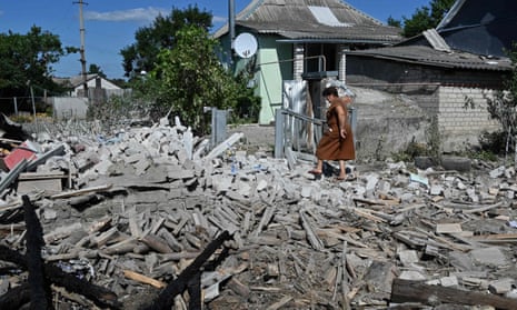 A lightly injured woman walks among the debris of a neighbour’s destroyed home after shelling in a village near Kupiansk, Ukraine
