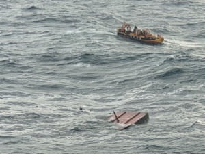 A rescue vessel searches for missing people near a fishing boat that caught fire off Jeju, South Korea