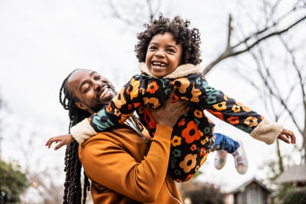 Father giving his young daughter an airplane ride in front of their home