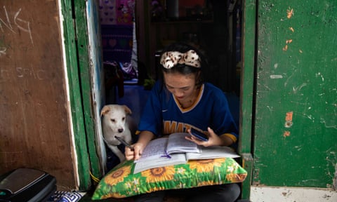 Annie Sabino, 16, tries to do her school work while working at her family’s food stall in the Philippines in January. 