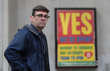 Burnham alongside a sign reading ‘Yes we’re open’