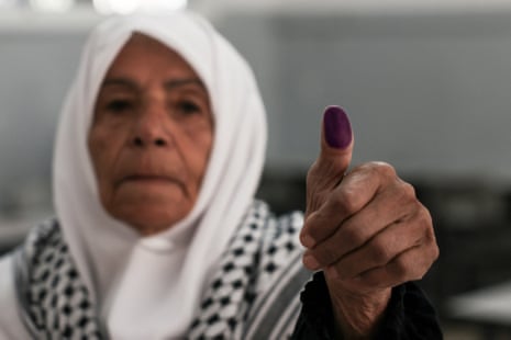 A Palestinian woman shows her marked finger after casting her ballot in a polling station