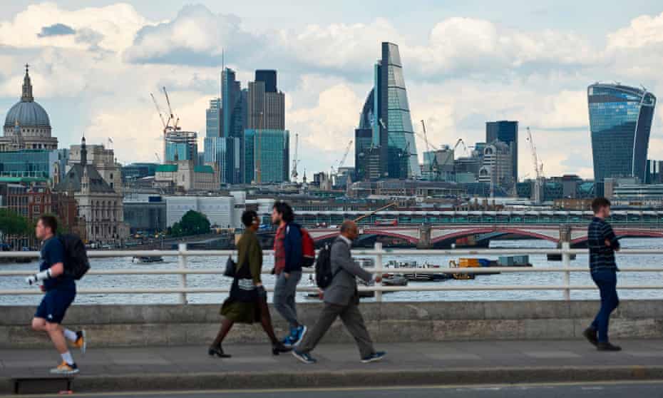 Pedestrians on Waterloo bridge with City of London skyline in background