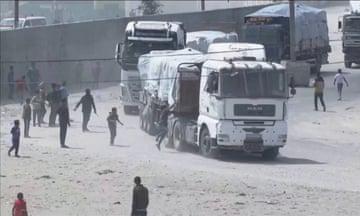 People running towards a convoy of lorries carrying aid