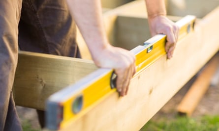 Cropped image of carpenter’s hands checking level of wood at construction site