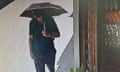 Michael Mosley shields himself from the sun with an umbrella as he walks along a street.