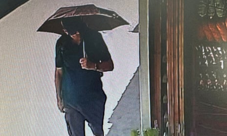 Michael Mosley shields himself from the sun with an umbrella as he walks along a street.