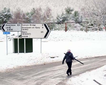 A person carrying skis walks along a road
