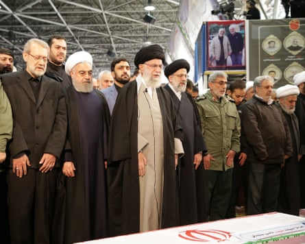 Larijani and others stand in front of a coffin