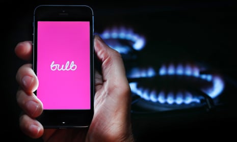 A man looking at the website logo for energy company Bulb on his phone in front of his gas cooker.