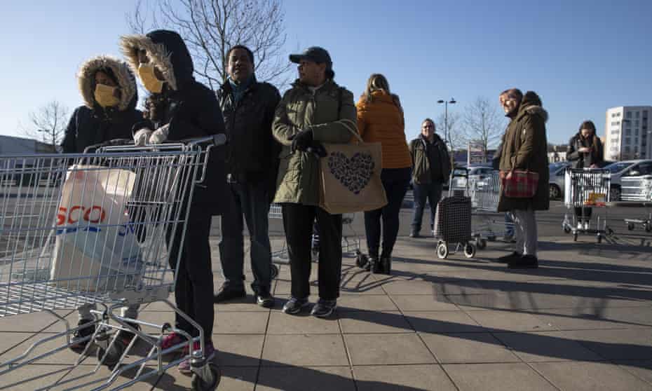 Shoppers queue outside a supermarket in London, 23 March 2020
